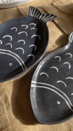 Ocean Fish Dinnerware Set A unique fish-shaped stoneware dinnerware collection in a rich dark blue color with charming hand-painted white details. It adds a modern, sea-inspired touch to your dining table.