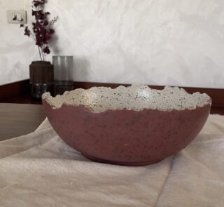 An extra-large stoneware serve bowl with a beautiful cream color and natural dark speckles. It features unique, rough edges for a natural look. With its huge size, it is perfect for serving big family salads, fruits, or hosting guests.