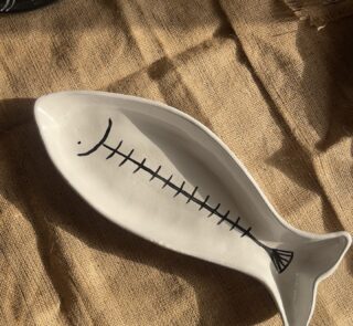 Azura Serving Platter Crafted from durable stoneware, this beautiful fish-shaped serving platter stands out with its clean white glaze and artistic hand-painted black fishbone design. It is perfect for adding a stylish sea-inspired vibe to any meal.