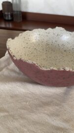 An extra-large stoneware serve bowl with a beautiful cream color and natural dark speckles. It features unique, rough edges for a natural look. With its huge size, it is perfect for serving big family salads, fruits, or hosting guests.