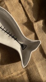 Azura Serving Platter Crafted from durable stoneware, this beautiful fish-shaped serving platter stands out with its clean white glaze and artistic hand-painted black fishbone design. It is perfect for adding a stylish sea-inspired vibe to any meal.