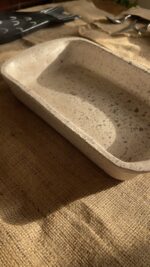 Pebble Oven Dish A beautiful rectangular stoneware dish with a warm sandy color and natural dark speckles. Perfect for both baking in the oven and serving directly on the table. It is great for making family meals, pasta, or roasted dishes.