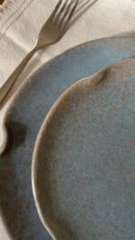Remnant Dinnerware Plate Inspired by the quiet traces of nature, this organic stoneware plate features unique speckled textures and artfully distorted rims. The calming harmony of sky blue and rock grey makes the Remnant set less of a dinnerware and more of a sculpted art piece for your dining space.