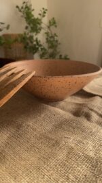 Conical Serve Bowl A large and beautiful stoneware serve bowl with a warm sandy color and natural dark speckles. With its wide shape, it is perfect for serving big family salads, fruits, or main dishes.