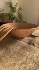 Conical Serve Bowl A large and beautiful stoneware serve bowl with a warm sandy color and natural dark speckles. With its wide shape, it is perfect for serving big family salads, fruits, or main dishes.