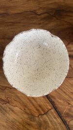 An extra-large stoneware serve bowl with a beautiful cream color and natural dark speckles. It features unique, rough edges for a natural look. With its huge size, it is perfect for serving big family salads, fruits, or hosting guests.