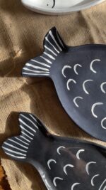 Ocean Fish Dinnerware Set A unique fish-shaped stoneware dinnerware collection in a rich dark blue color with charming hand-painted white details. It adds a modern, sea-inspired touch to your dining table.