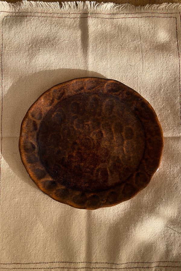 Bark Side Plate A beautiful stoneware side plate with a shiny mix of brown and honey colors. Handcrafted with a natural round shape, it is perfect for serving your daily sides, desserts, or small snacks.
