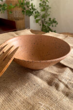Conical Serve Bowl A large and beautiful stoneware serve bowl with a warm sandy color and natural dark speckles. With its wide shape, it is perfect for serving big family salads, fruits, or main dishes.