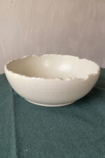 Ivory Serve Bowl A beautiful stoneware serve bowl with a soft creamy white color. It features unique, rough edges for a natural touch. With its perfect size, it is great for serving salads, hot soups, or daily dishes.