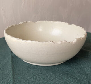 Ivory Serve Bowl A beautiful stoneware serve bowl with a soft creamy white color. It features unique, rough edges for a natural touch. With its perfect size, it is great for serving salads, hot soups, or daily dishes.