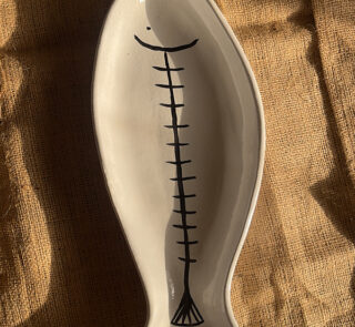 Azura Serving Platter Crafted from durable stoneware, this beautiful fish-shaped serving platter stands out with its clean white glaze and artistic hand-painted black fishbone design. It is perfect for adding a stylish sea-inspired vibe to any meal.