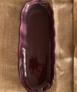 Homura Artisan Platter Captivating with its rich burgundy glaze and gently scalloped rim, this expansive stoneware platter brings a touch of dramatic warmth to your table. Its low, sleek profile makes it an exquisite backdrop for artistic food presentation or a striking accent piece for grand hosting.
